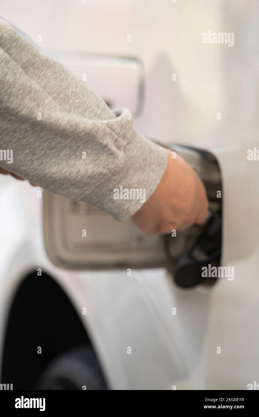 Close up shot of a hand opening car's fuel tank lid in white car