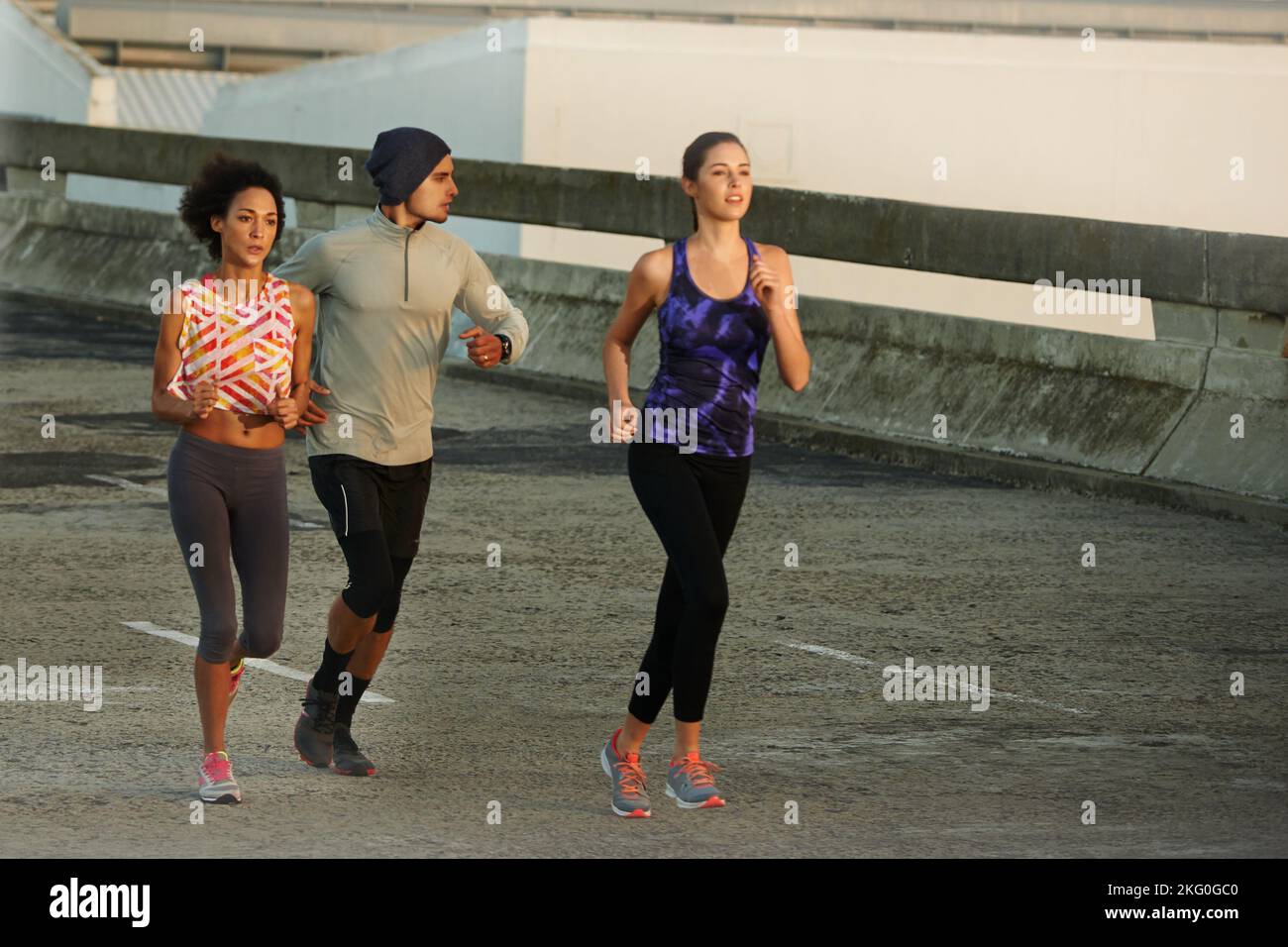 Freedom of an early morning run. three friends jogging together in the city at sunrise. Stock Photo