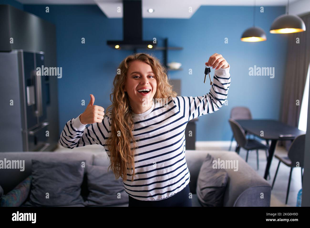 Happy woman showing new house or apartment keys to camera in modern interior. Female tenant renter with new home keys moving to tenancy. Lady Stock Photo