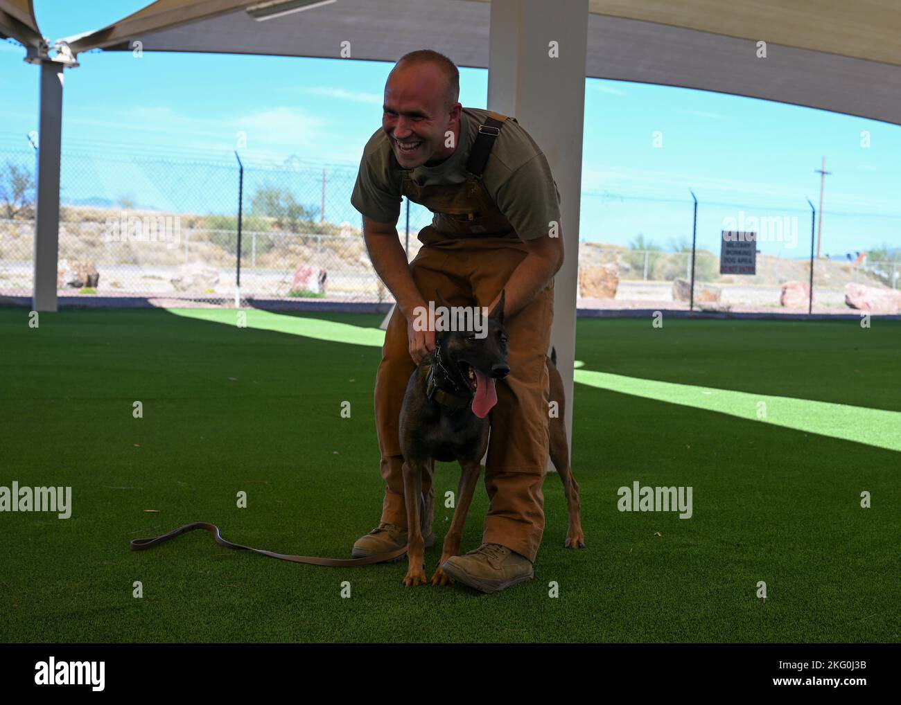 U.S. Air Force Staff Sgt. Shane Myers, 355th Security Forces Squadron military working dog handler, and Ssilke, 355th SFS MWD, pose for a photo following the conclusion of a MWD demonstration at Davis-Monthan Air Force Base, Arizona, Oct. 19, 2022. Each MWD that trains at the 'Puppy Program' at Lackland Air Force Base, Texas, has a double first letter in their name. The program allows qualified volunteers to foster puppies, providing them with learning and play opportunities. Stock Photo