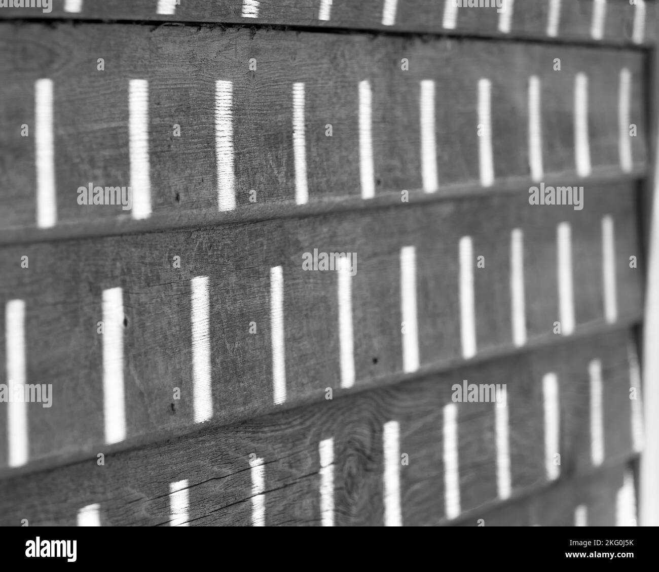 Black and white photo of the sunlight making patterns on a bench Stock Photo