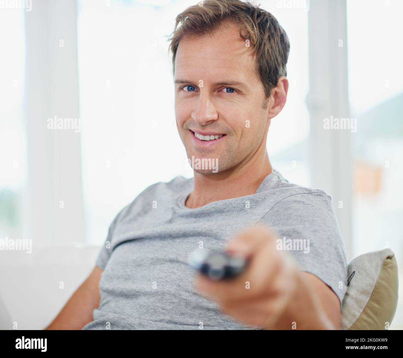 Parked in front of the tv. Portrait of a handsome man holding a remote ...