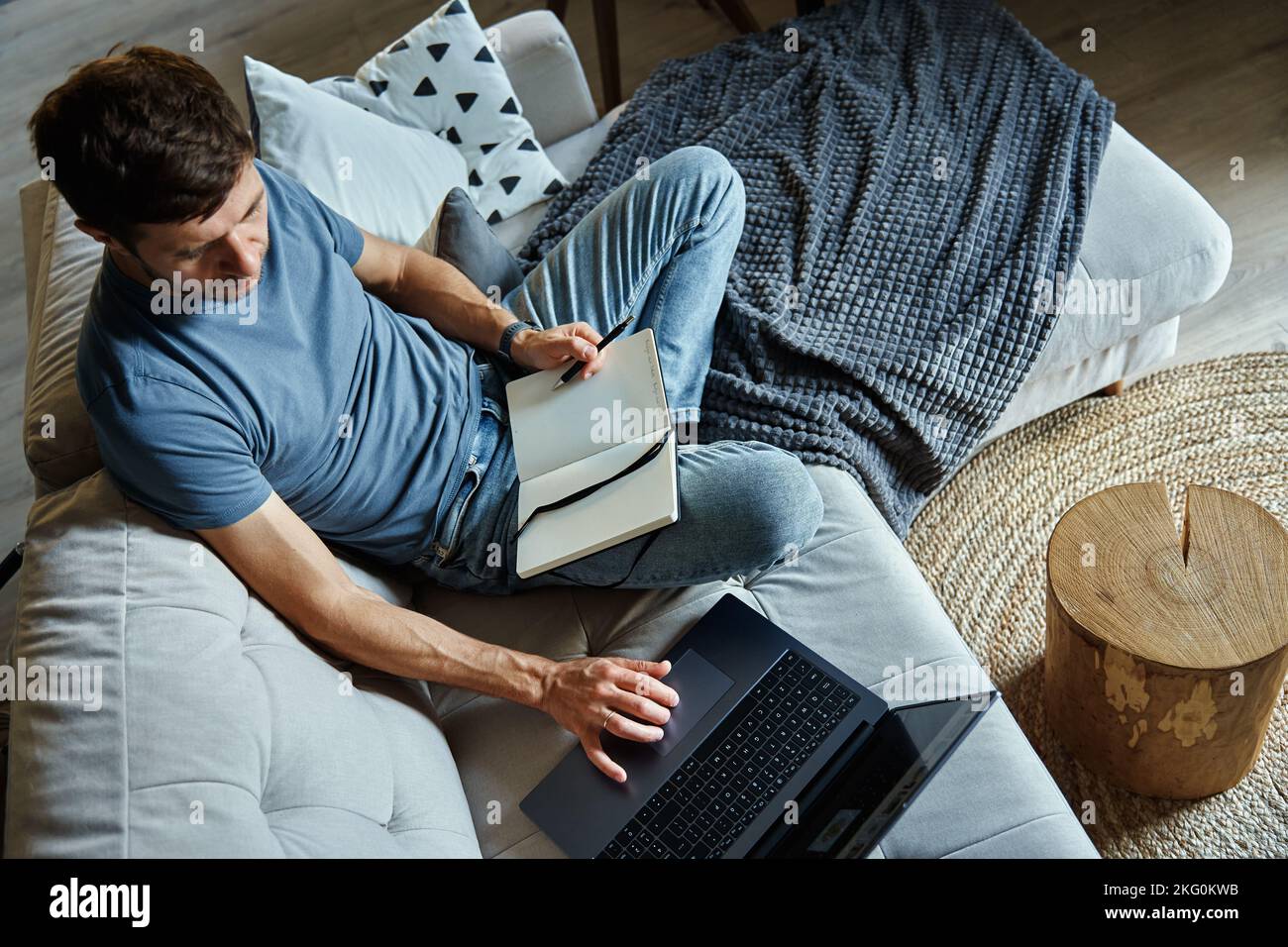 Above view of man sitting on sofa and using laptop. Freelancer working at home workplace. Remote work and work from home concept Stock Photo