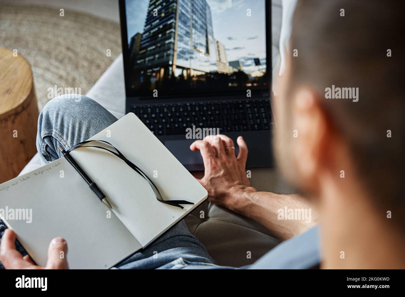 Man sitting on sofa and using laptop. Freelancer working at home workplace. Remote work and work from home concept Stock Photo
