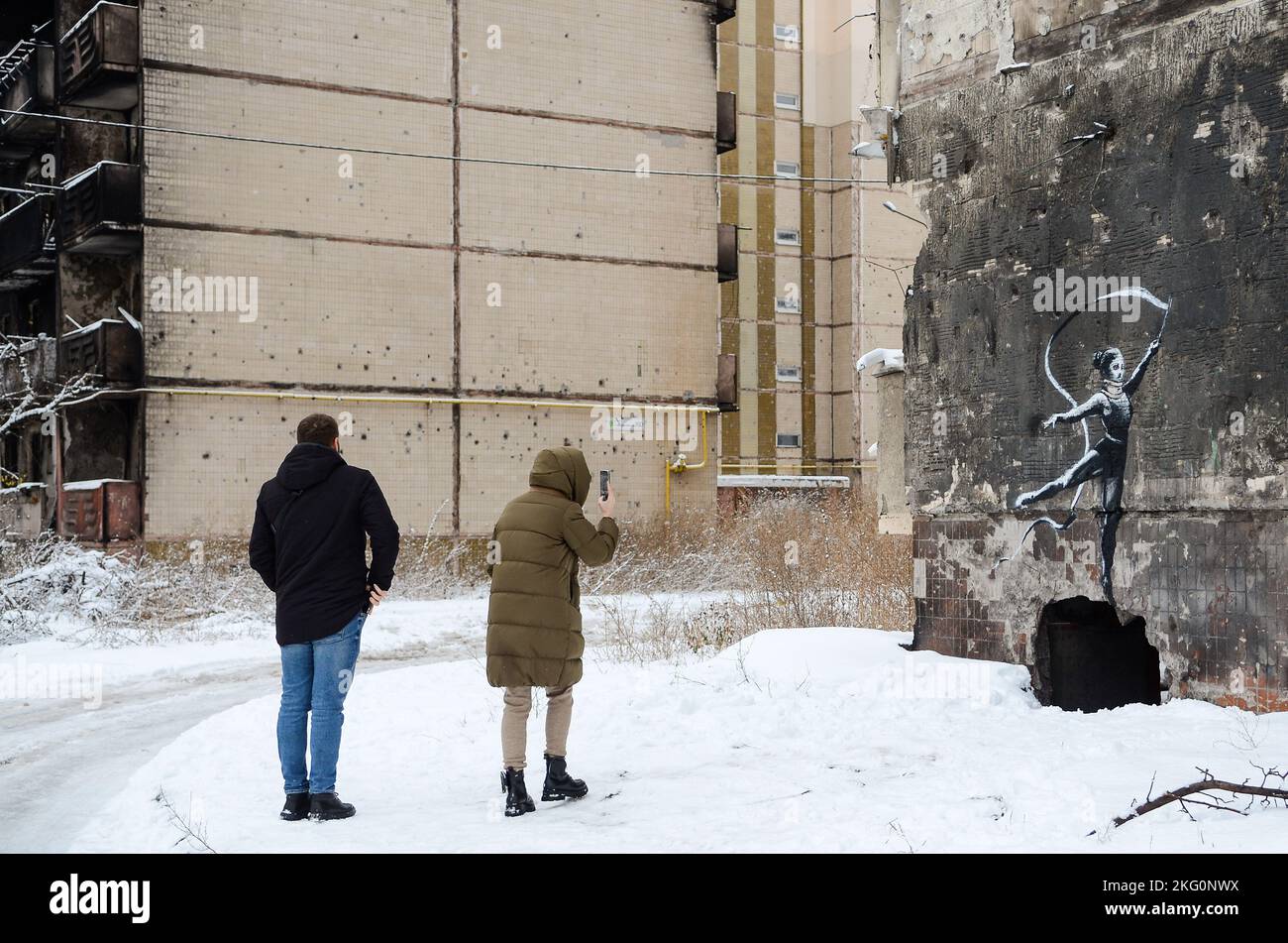 IRPIN, UKRAINE - NOVEMBER 19, 2022 - A woman takes a picture of the mural created by England-based street artist Banksy on the wall of the apartment b Stock Photo