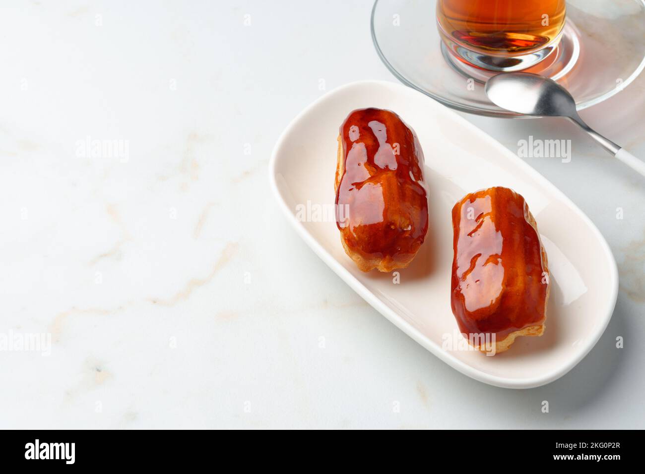 Two caramel eclairs on a white plate Stock Photo