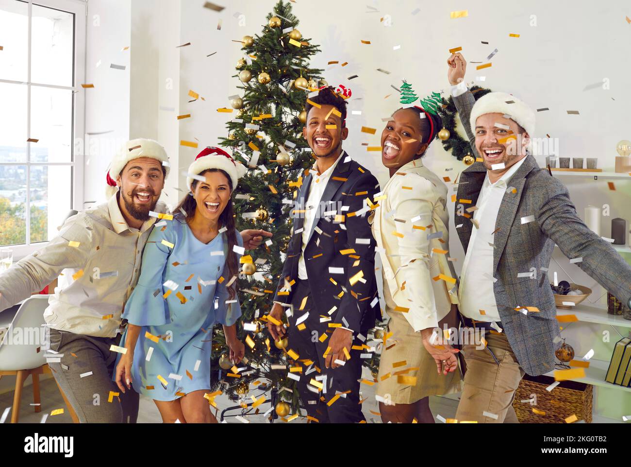 Group of happy joyful diverse friends having fun at Christmas party with confetti Stock Photo