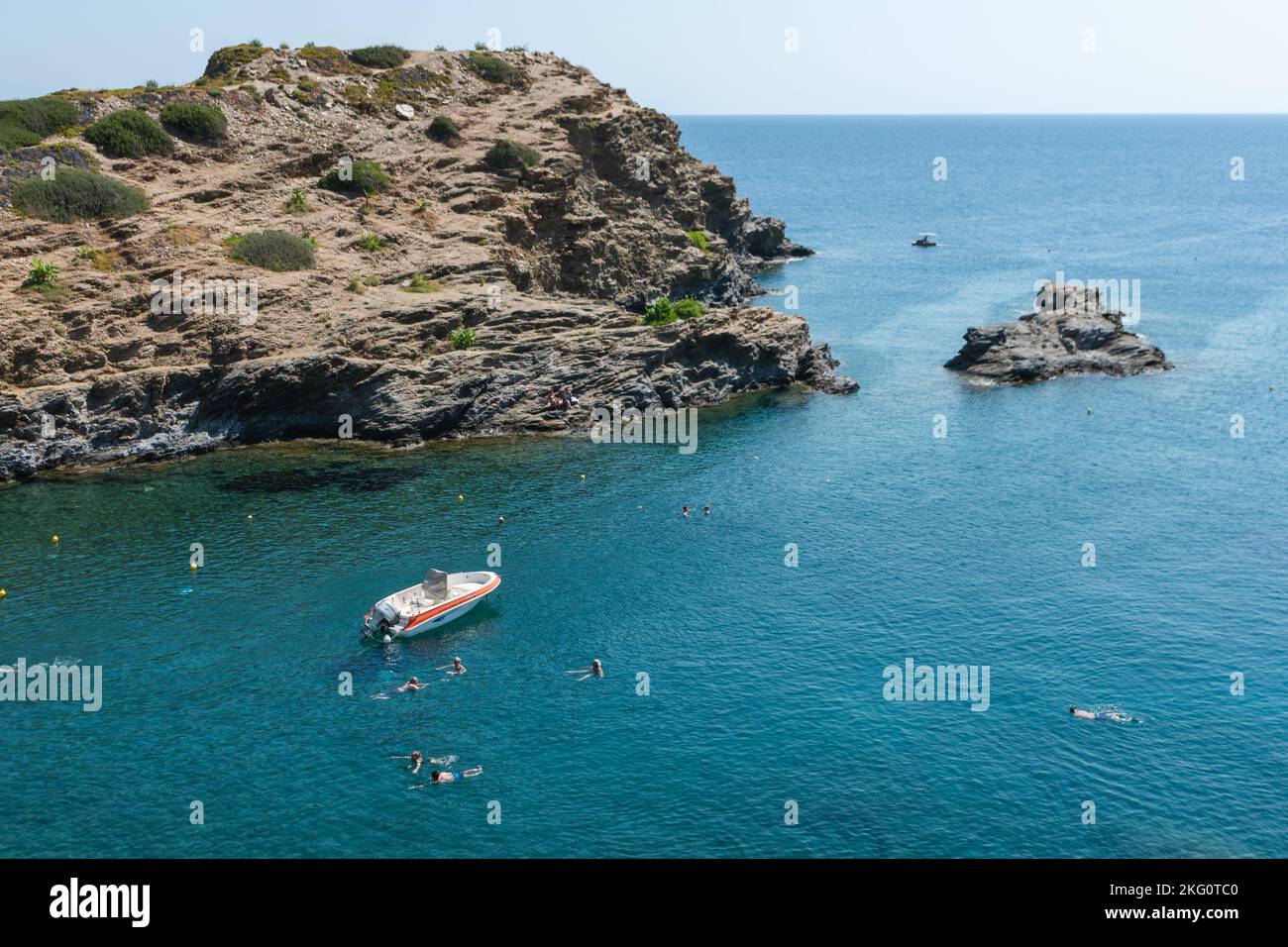 An aerial view of people swimming by the boat and a rocky island in the ...