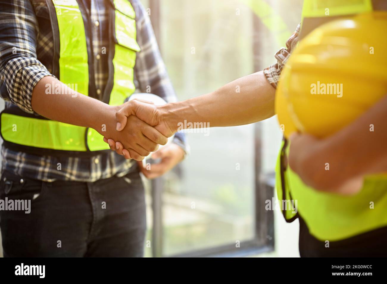 Professional and successful construction engineer or worker shaking hands with his coworker. close-up and cropped image Stock Photo