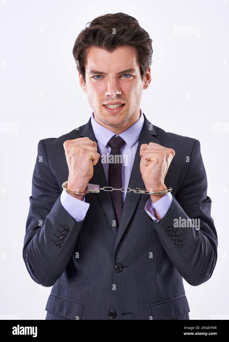 I need to break free of the corporate shackles. Studio shot of a handsome young businessman in handcuffs. Stock Photo