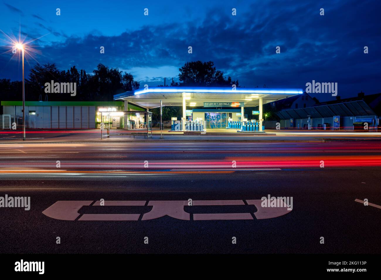 A gas station in the street at night with long exposure red and blue