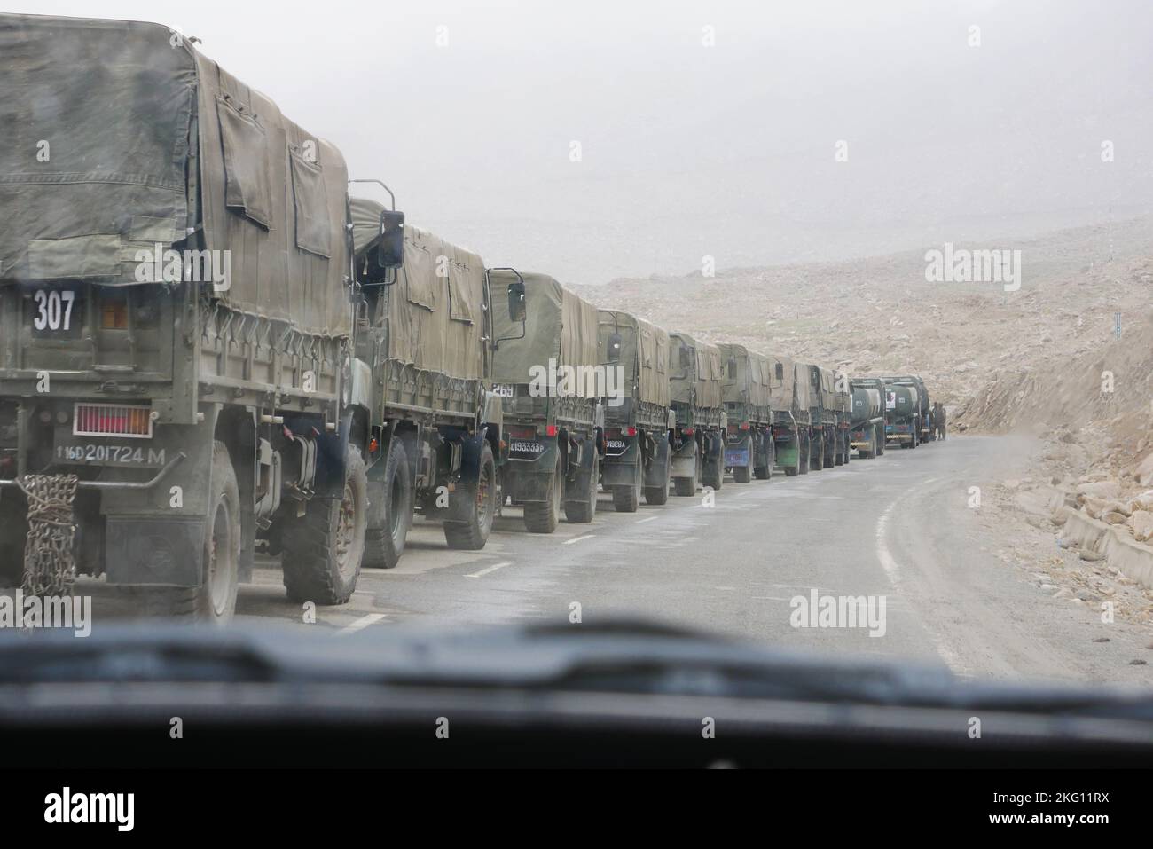 The Indian military army trucks driving through a deserted road Stock Photo