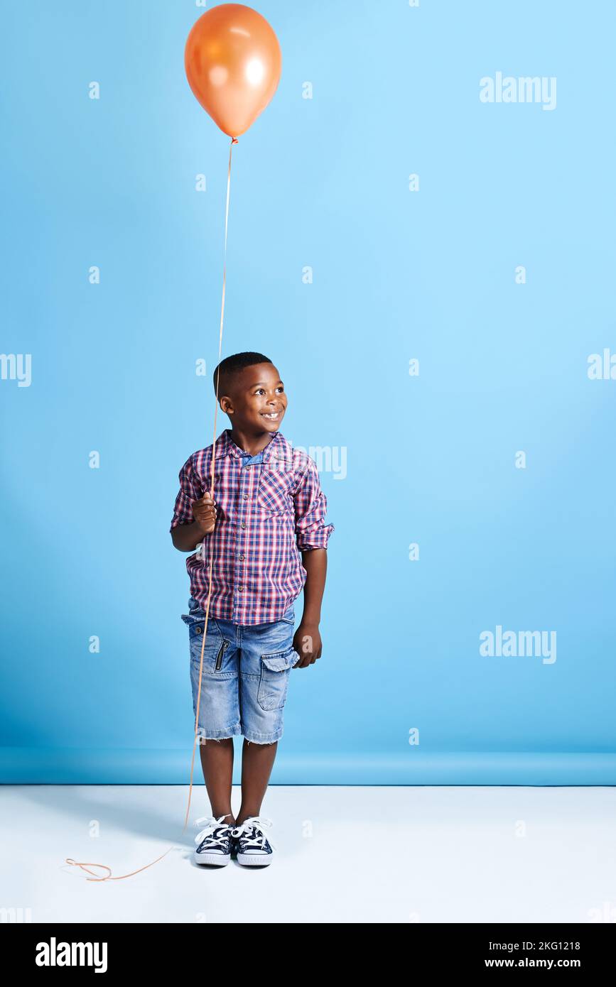 Ive got it all planned out. a young boy holding a balloon over a blue