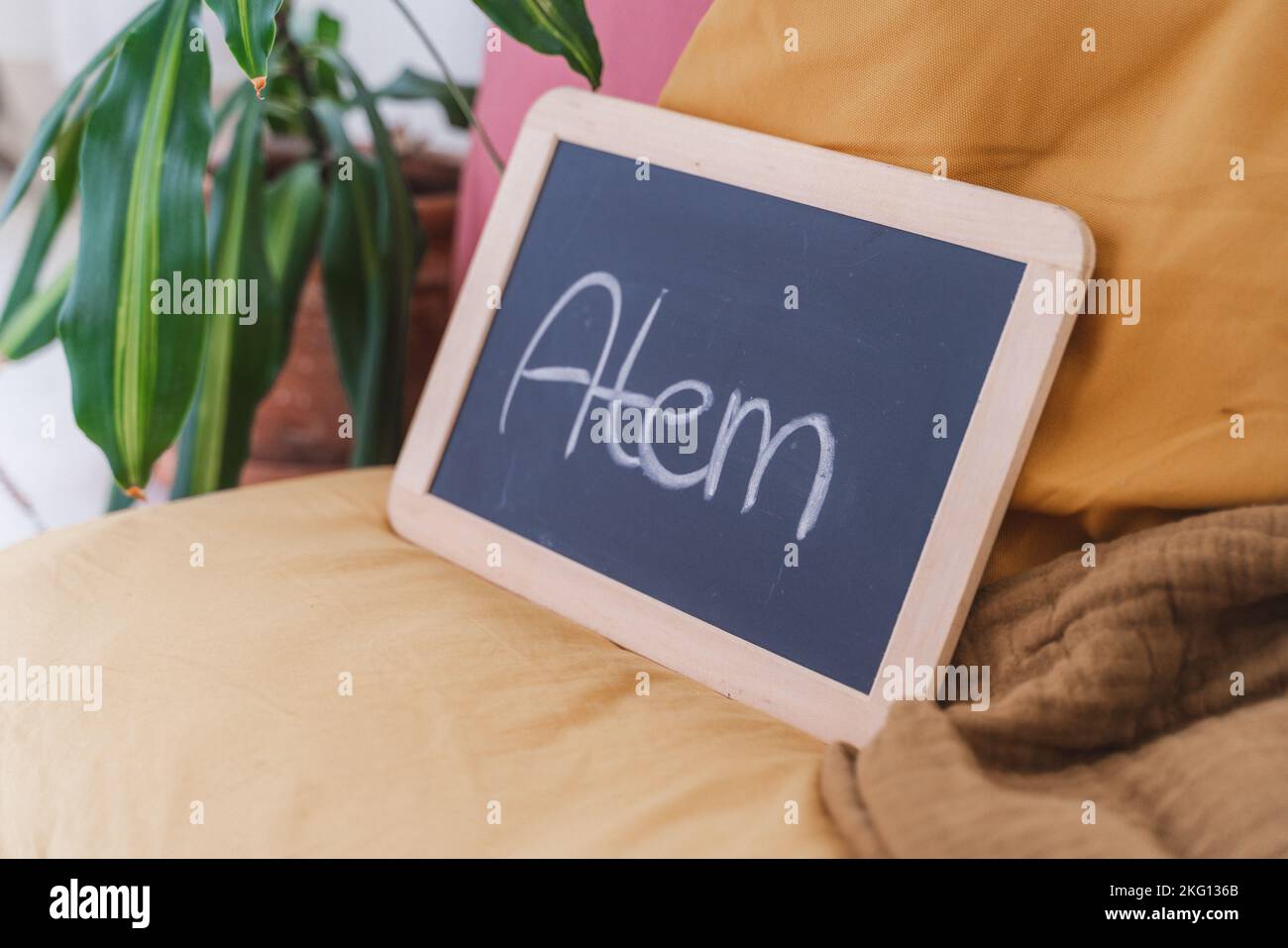 A small 'Atem' blackboard on a yellow pillow on the floor - Hypnobirthing concept Stock Photo