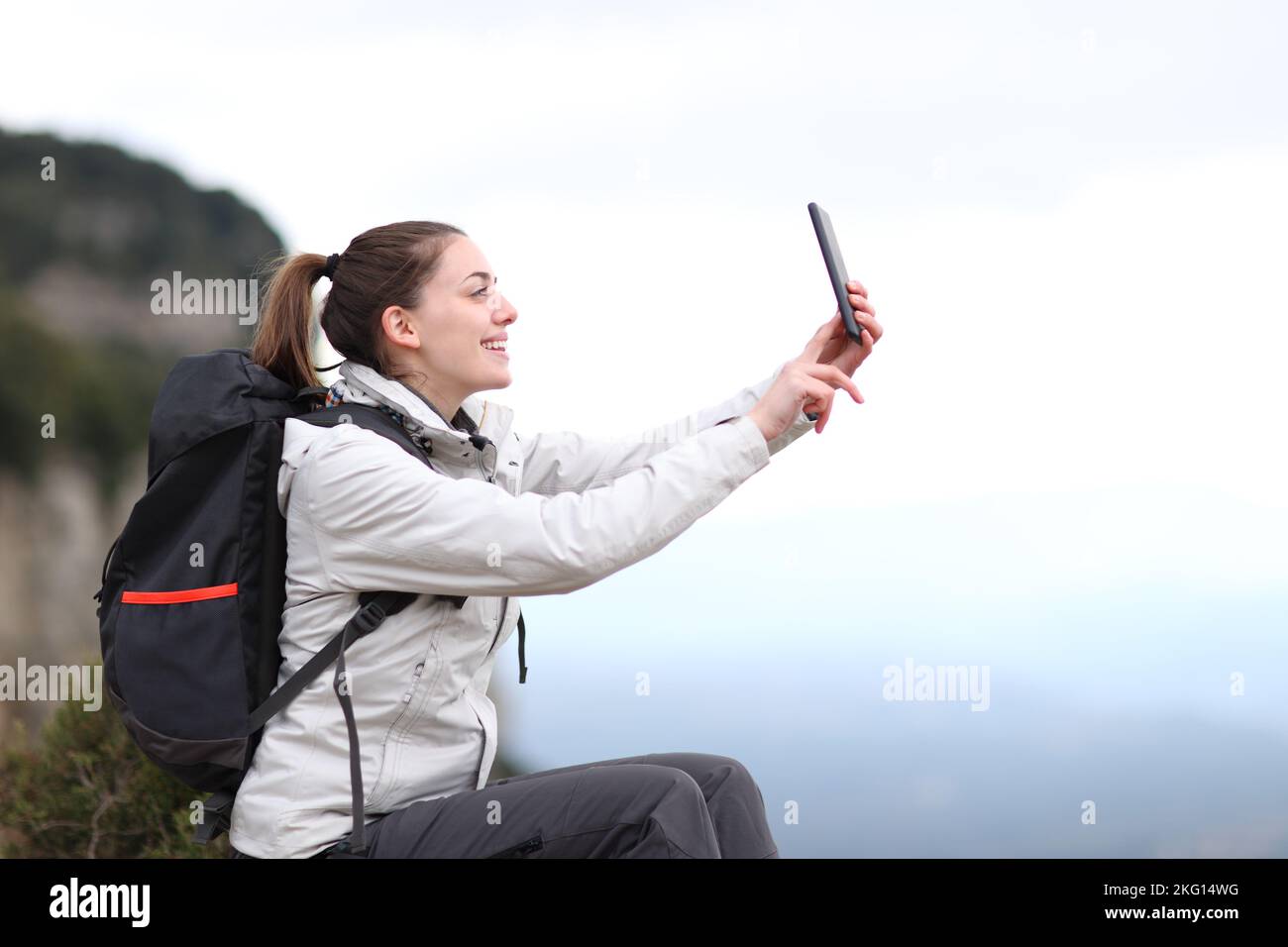 Side view portrait of a happy trekker taking selfie in the mountain Stock Photo
