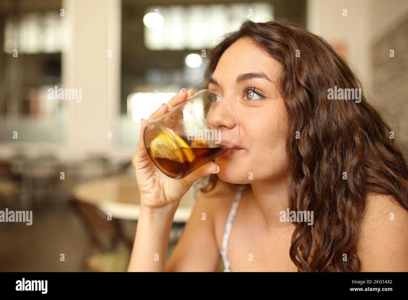 Happy woman drinking soda looking away in a bar Stock Photo