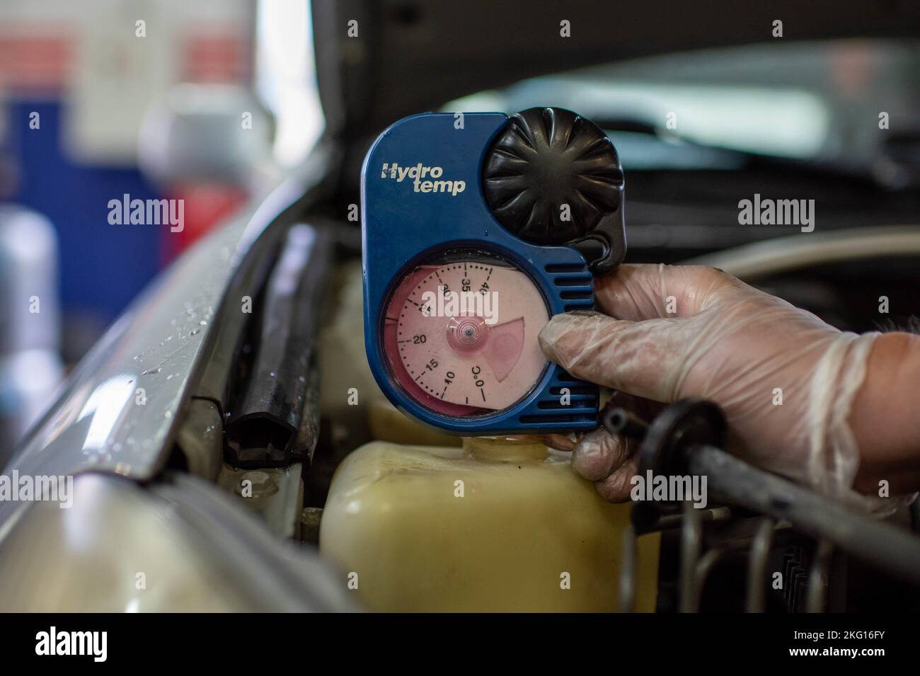 An automotive technician takes the temperature of a vehicle’s radiator