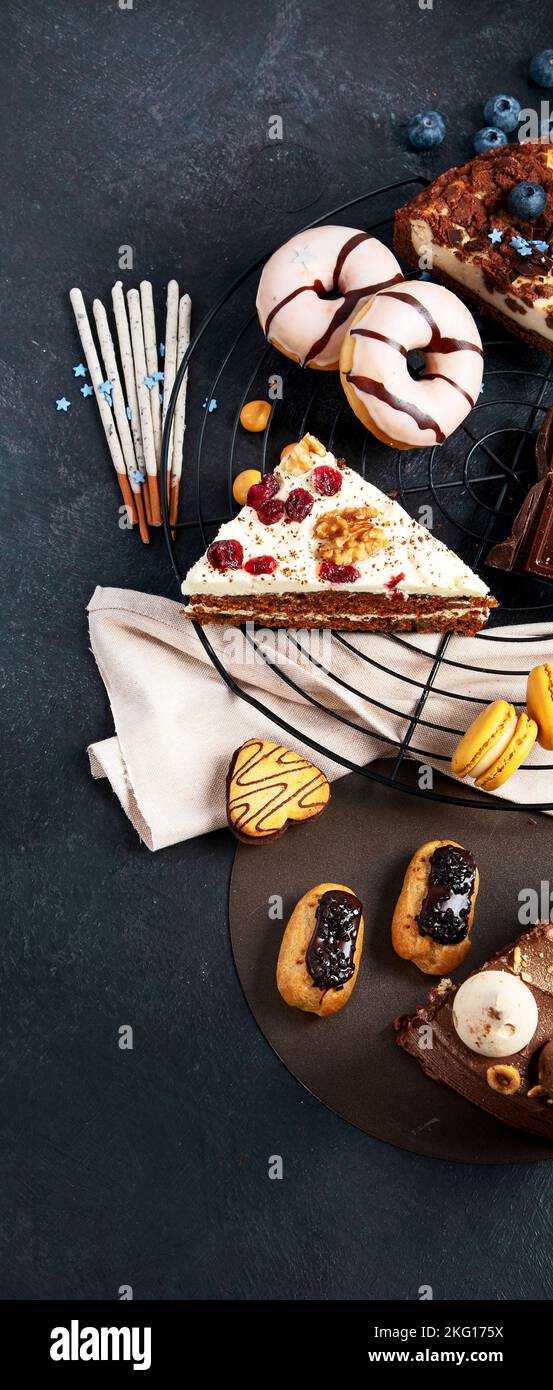 Table with various cookies, donuts, cakes, cheesecakes on dark background.  Delicious dessert table. Top view, flat lay Stock Photo