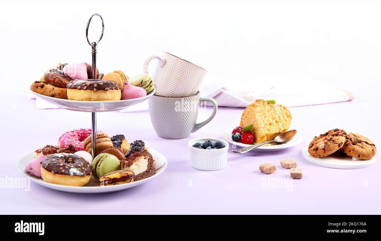 Traditional English tea. Afternoon tea with  selection of sweets  on violet background. Holiday concept Stock Photo