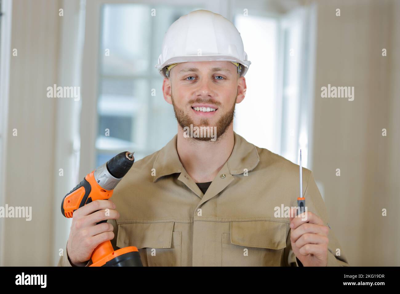 male builder holds a drill with a perforator Stock Photo