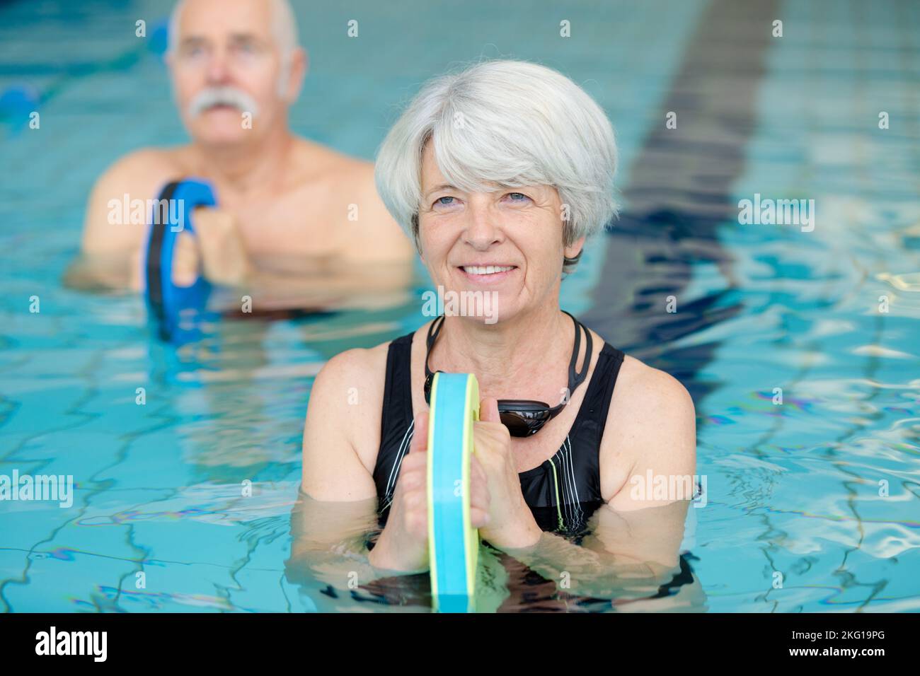 senior woman doing water exercise with kicking board Stock Photo