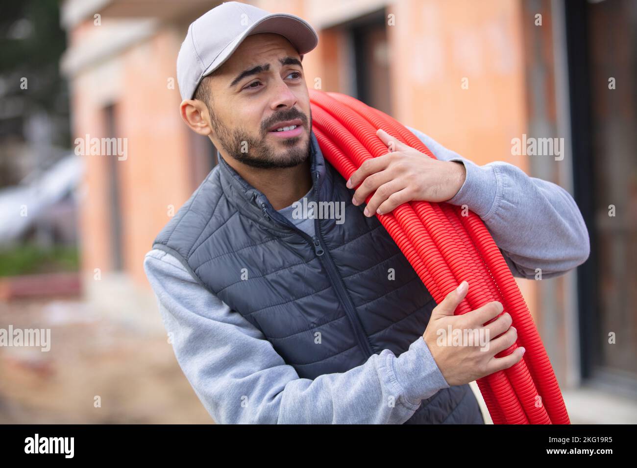 portrait of a smiling worker carrying corrugated conduit Stock Photo