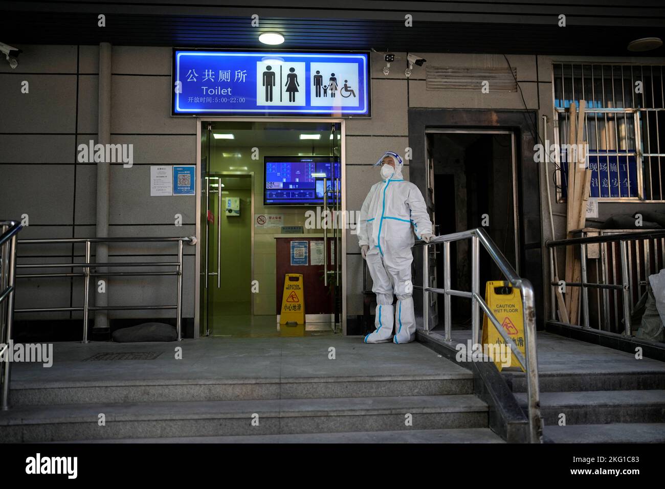 A worker in protective suit keeps a watch outside a public toilet to inspect the health code of visitors, amid the coronavirus disease (COVID-19) outbreak in Shanghai, China, November 21, 2022. REUTERS/Aly Song Stock Photo