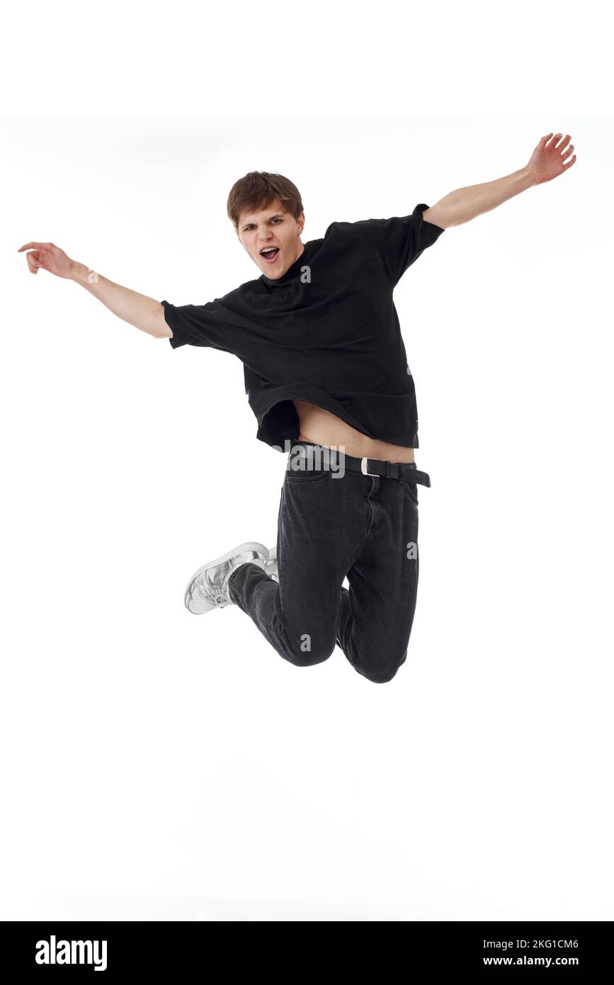young man in black t-shirt smiling jumping high Stock Photo