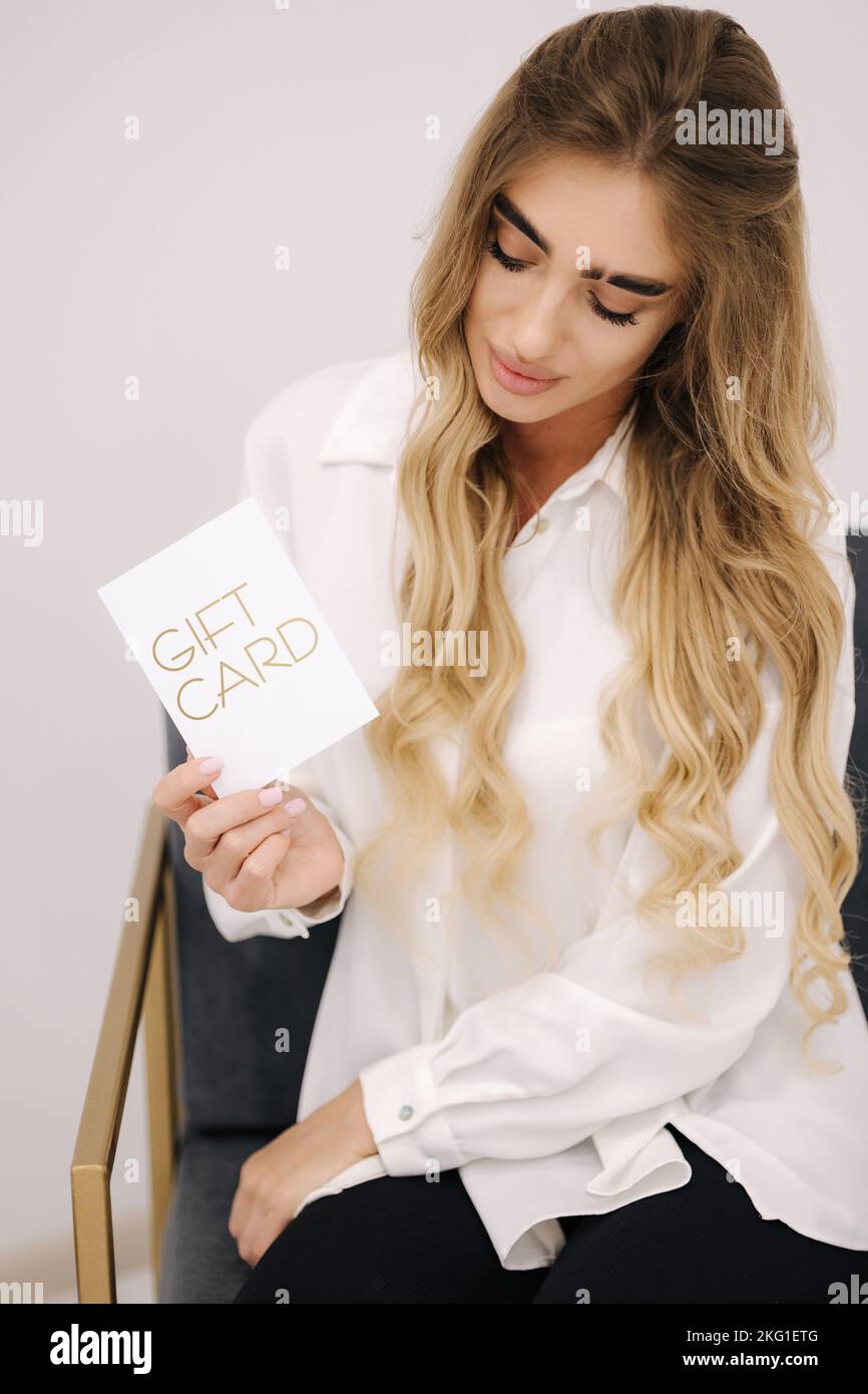 Woman hold gift card in hand. Beauty studio. Certificate for cosmetology procedyre Stock Photo