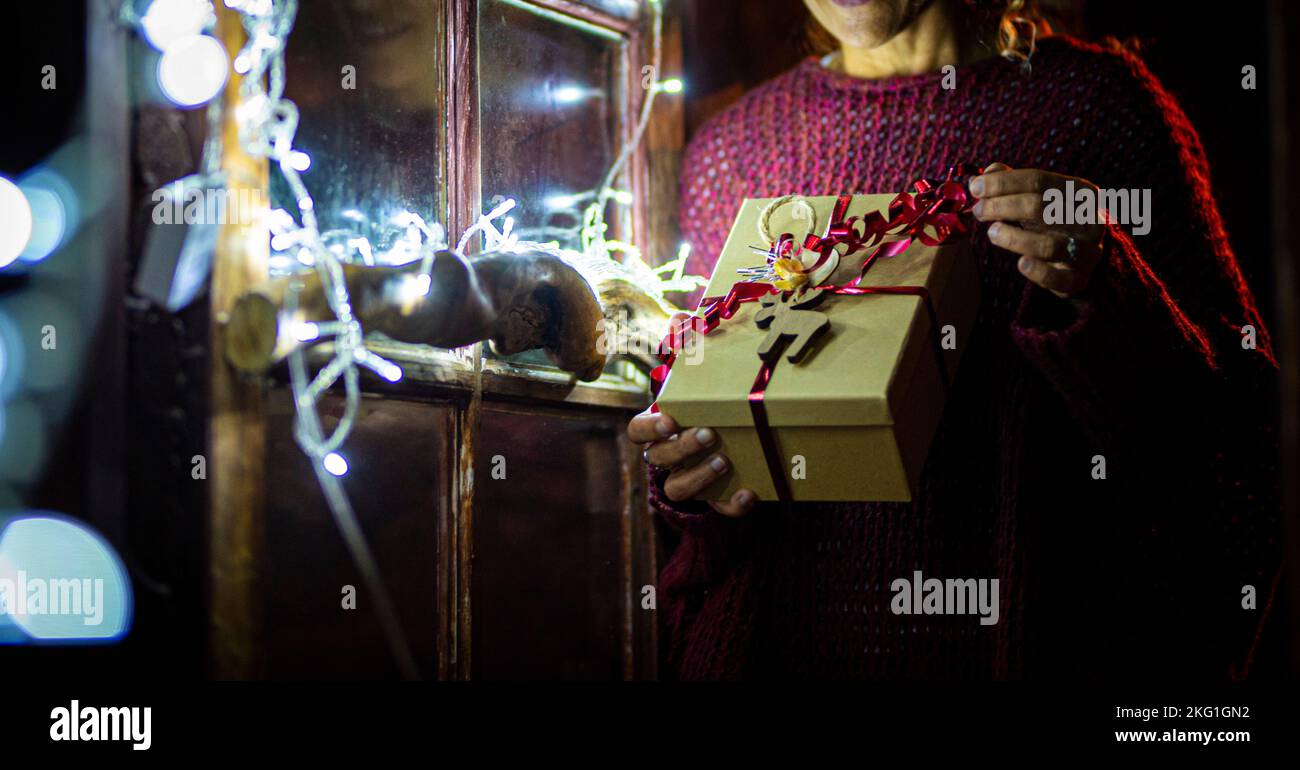 Close up banner image of christmas gifts present sharing. Woman unboxing red tape box for xmas eve night. Celebrating december holiday season at home. Stock Photo