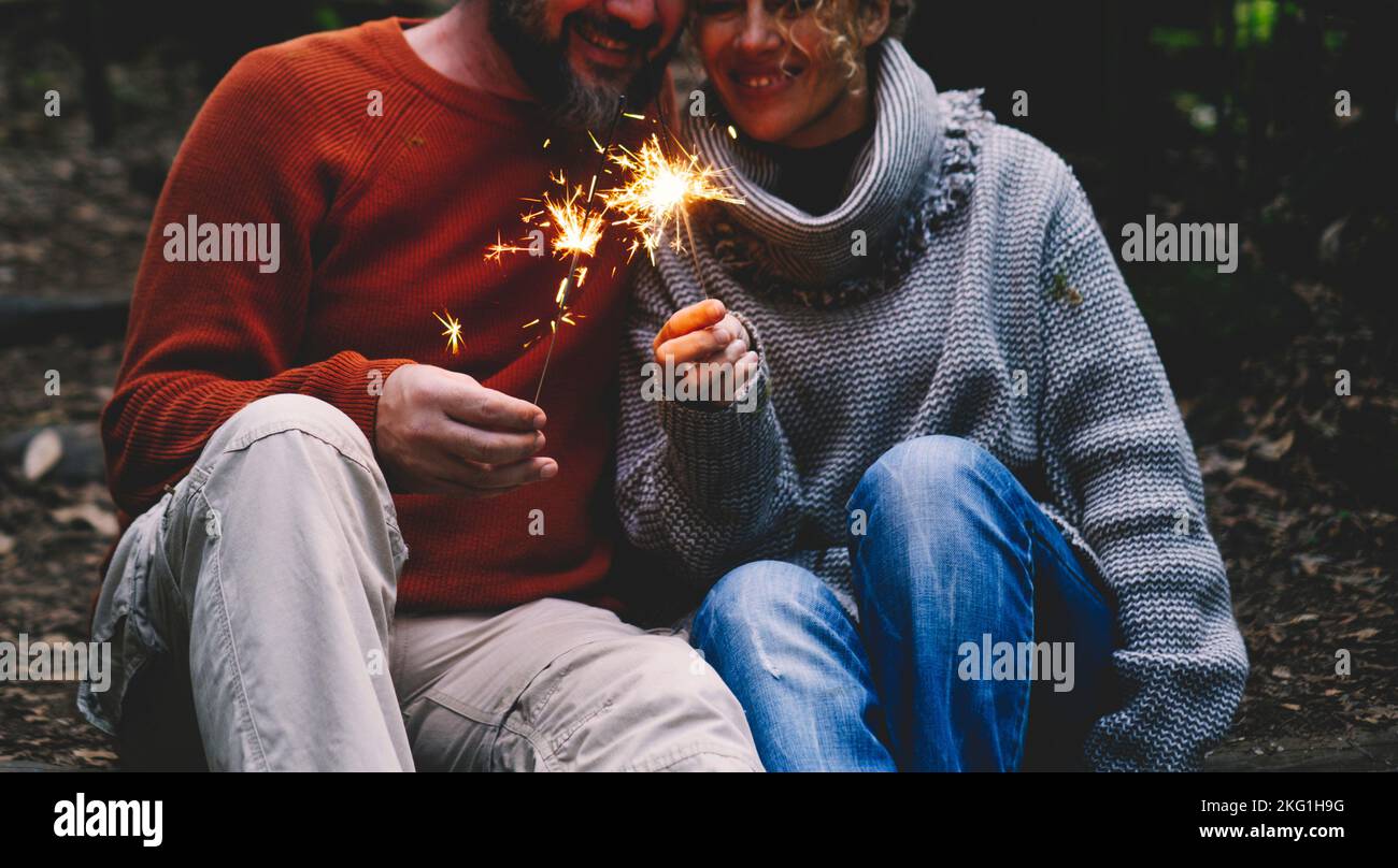 Man and woman in relationship celebrate together anniversary with sparkler lights in outdoors leisure activity. Romance and romantic people celebratin Stock Photo