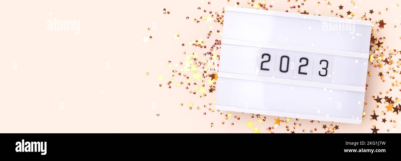 Lightbox with 2024 numbers and gold colored stars confetti on a beige background. New Year concept with place for text. Stock Photo