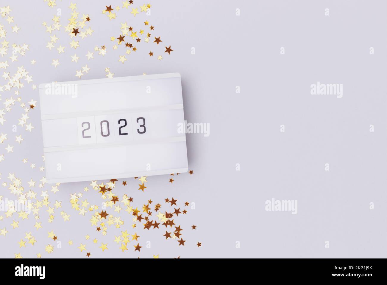 Lightbox with 2023 numbers on a blue pastel background with golden stars confetti. Place fof text. Stock Photo