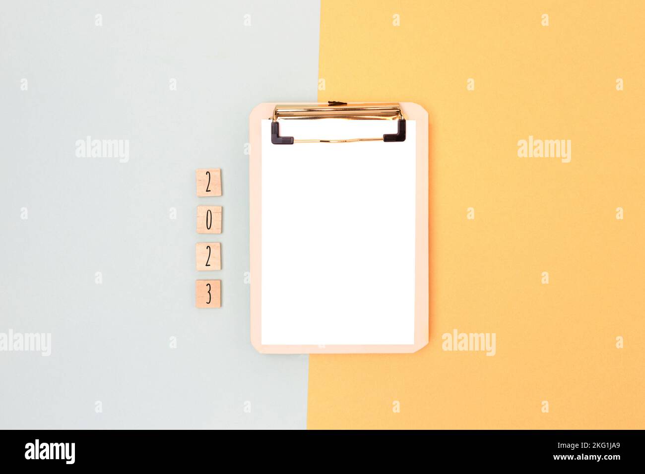 Clipboard with paper mockup and wooden blocks with 2023 numbers on a