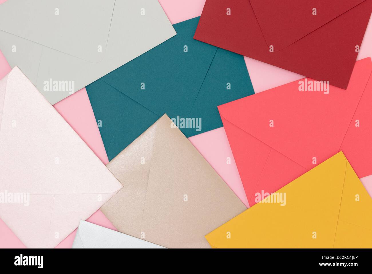 Multicolored envelopes scattered on a pink background. Creative background. Stock Photo