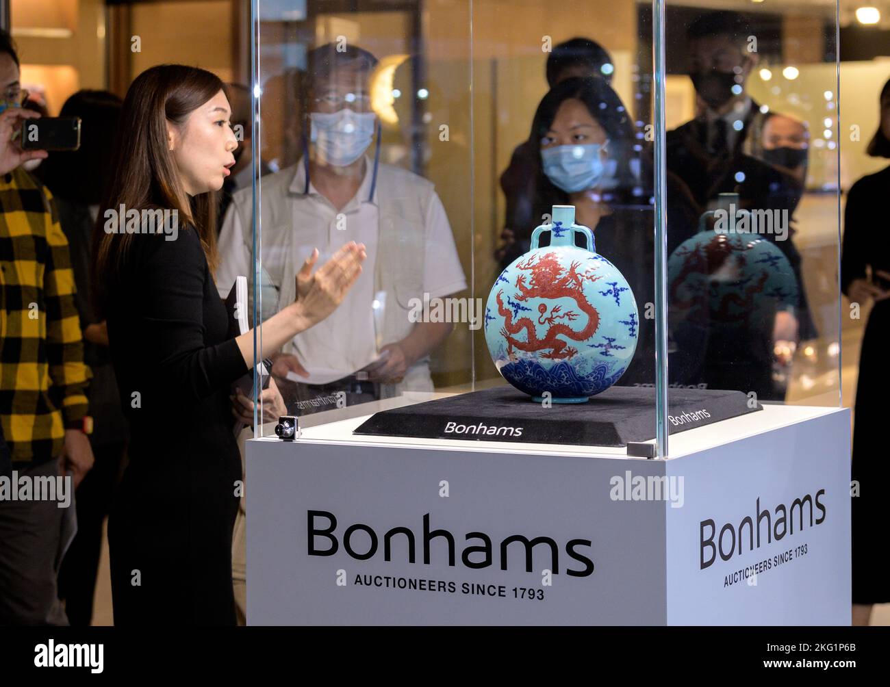 Hong Kong, China:21 Nov, 2022. Bonhams Chinese Ceramics and Works of Art Sales Gigi Yu (L), Bonhams Head of Chinese Ceramics and Works of Art, shows off The Liddell Moonflask. One of only three known surviving turquoise-ground underglaze-blue and copper-red ‘dragon' Qianlong (fourth Qing emperor to rule over China proper, reigning from 1735 to 1796) moonflasks emerges onto market after a decade. The exceptionally rare Liddell Moonflask from the prestigious Huaihaitang Collection（懷海堂）from Hong Kong carries an estimate of HK$18,000,000-25,000,000 Alamy Live news/Jayne Russell Stock Photo