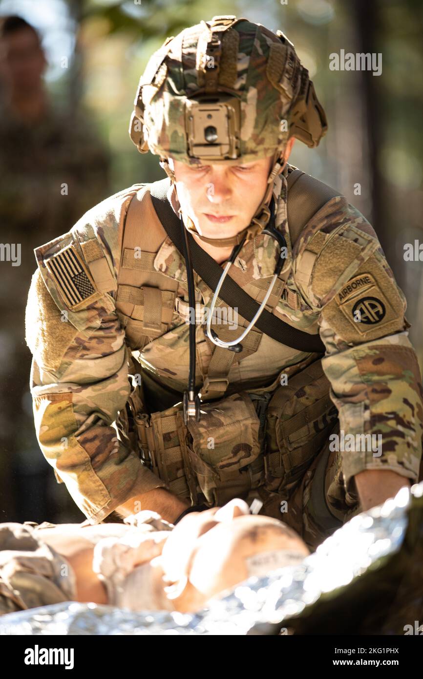 A competitor with the 82nd Airborne Division, reviews a simulated patient for awareness during an during a Expert Field Medical Badge lane at Fort Bragg, N.C., Oct. 25, 2022. More than 100 Soldiers are testing on a variety of medical skills in an effort to earn the coveted EFMB. The EFMB is a United States Army decoration first created on June 18, 1965. This badge is the non-combat equivalent of the Combat Medical Badge and consists of a Physical Fitness Assessment , Written Test, Day and Night Land Navigation, Three Combat Testing Lanes, and a 12 Mile Foot March. Stock Photo