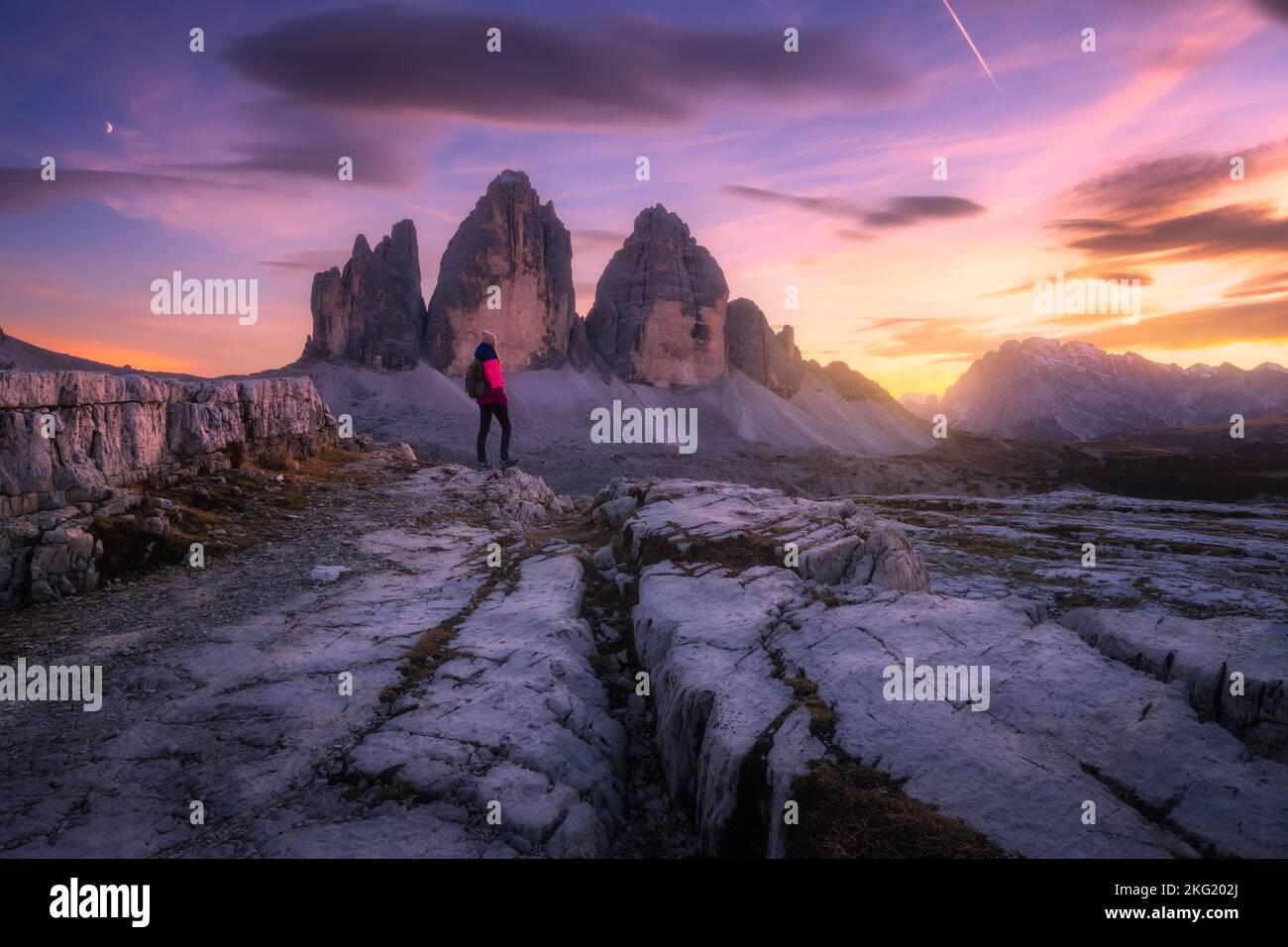 Girl on the mountain peak and high rocks at colorful sunset Stock Photo