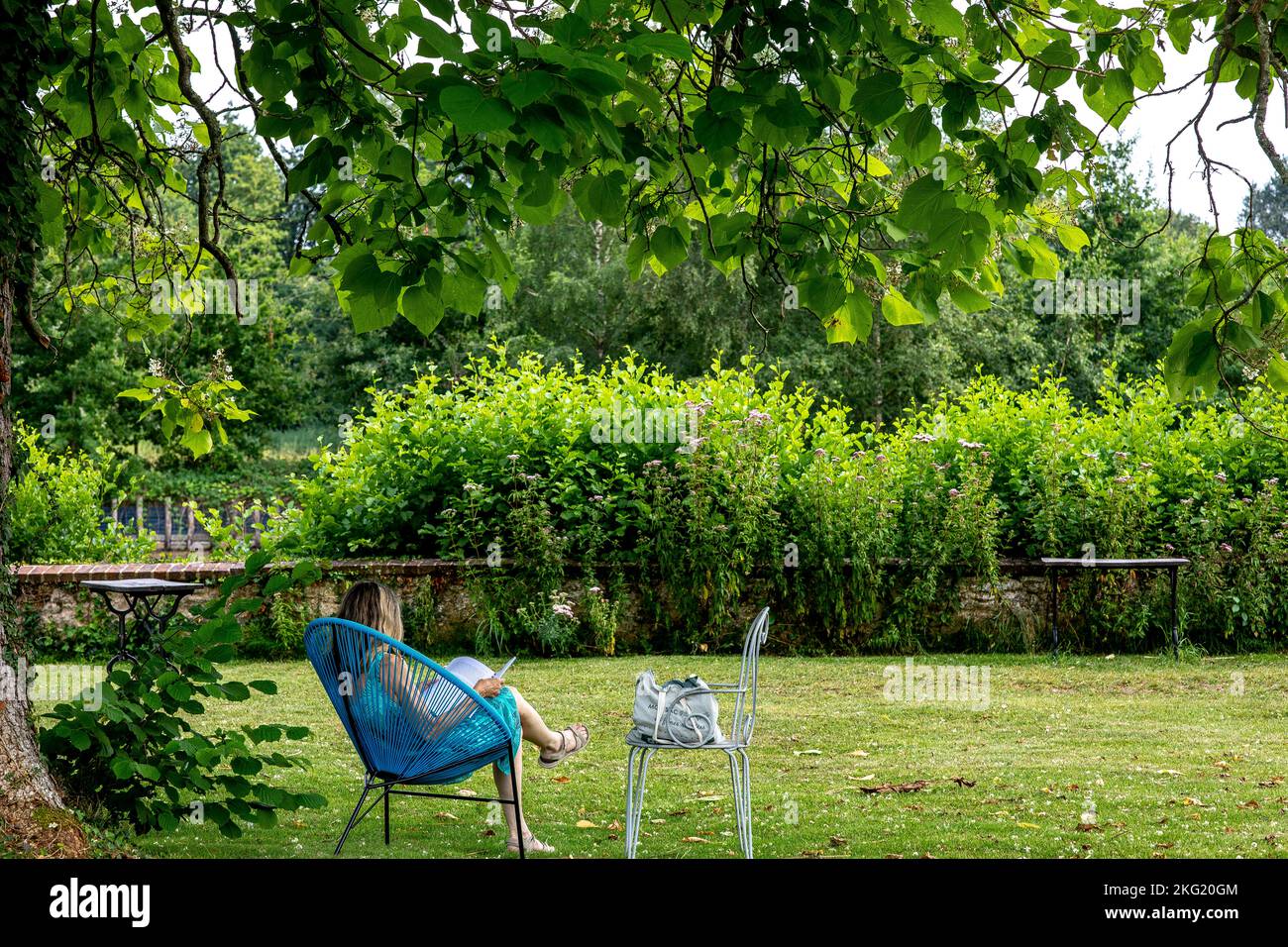 Adult reading in an armchair in a garden in western France Stock Photo