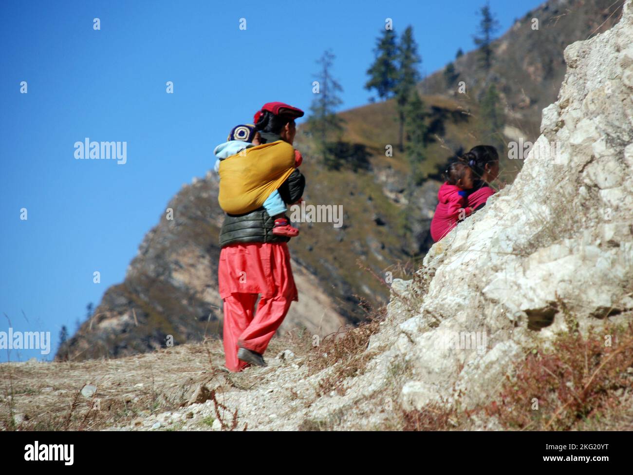 A Nepali woman carrying a baby on a high trail in shey phoksundo national park Nepal Stock Photo