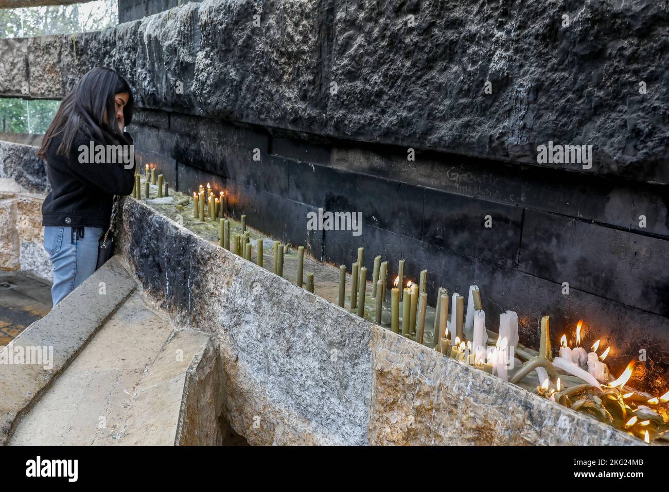 Young woman lighting candles in Our Lady of Lebanon sanctuary, Harissa