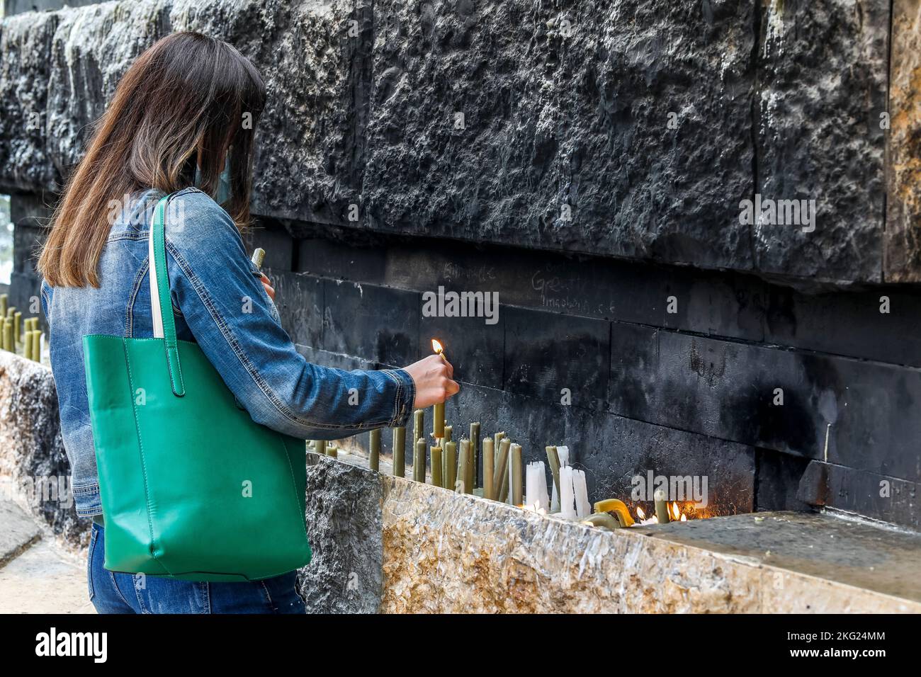 Young woman lighting candles in Our Lady of Lebanon sanctuary, Harissa