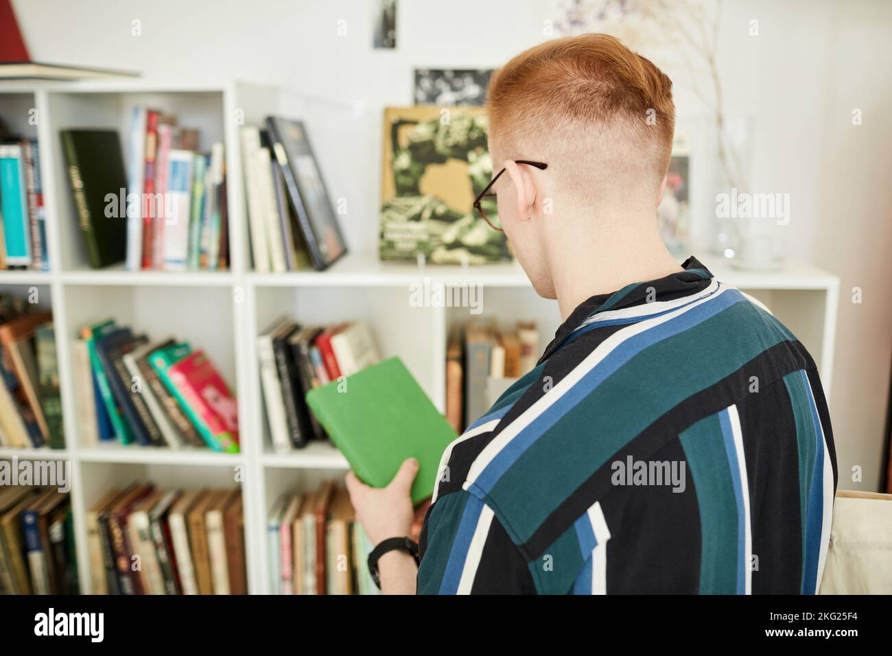Back view of young man buying used books in thrifting shop or swap