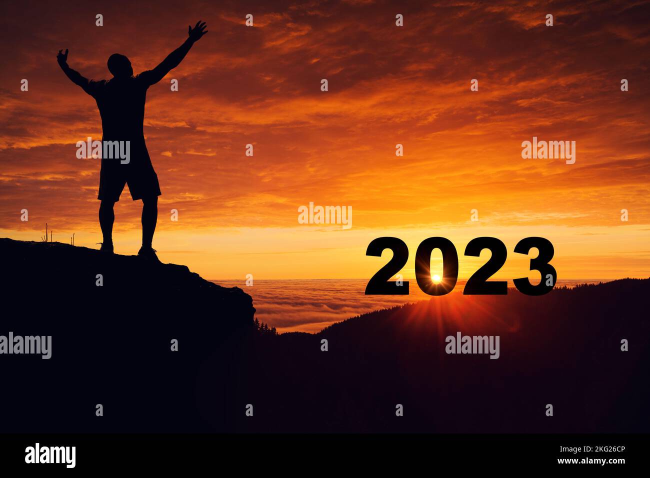 Man silhouette on the mountain top watching the sunrise and 2023 years while celebrating. Stock Photo