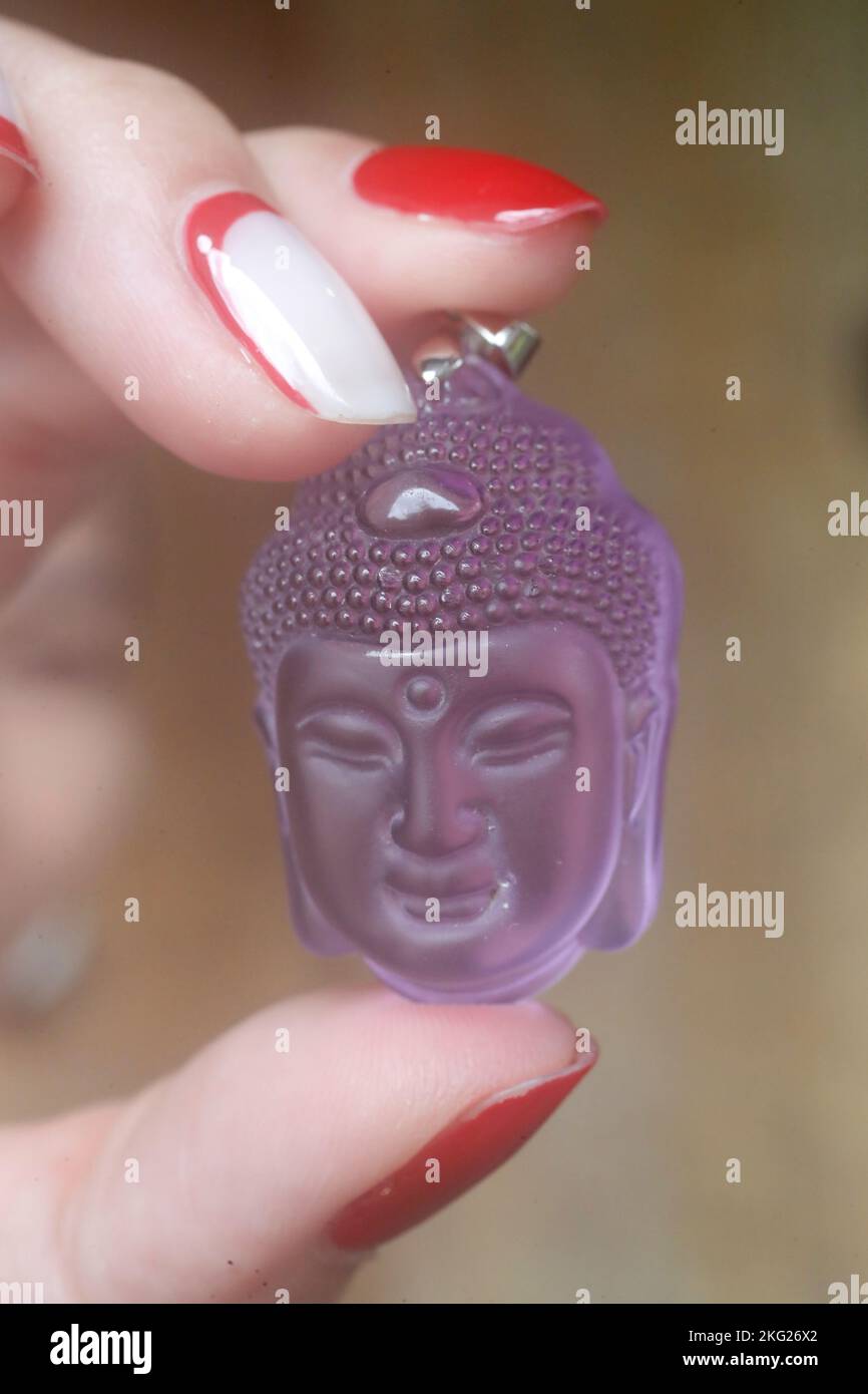 Pink Buddha head pendant in hand. Buddhist symbol Stock Photo Alamy