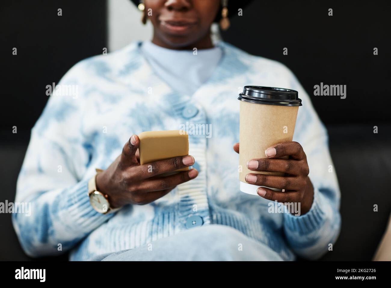 Close up of young black woman using smartphone and holding coffee cup, gen Z communication concept Stock Photo