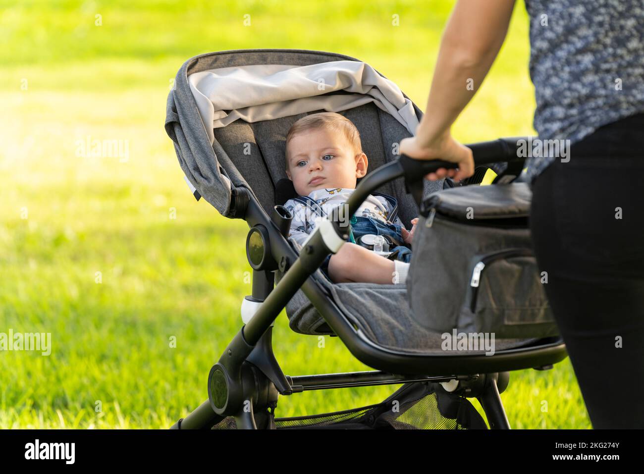 Mother and son walking with the baby stroller in the park Stock Photo