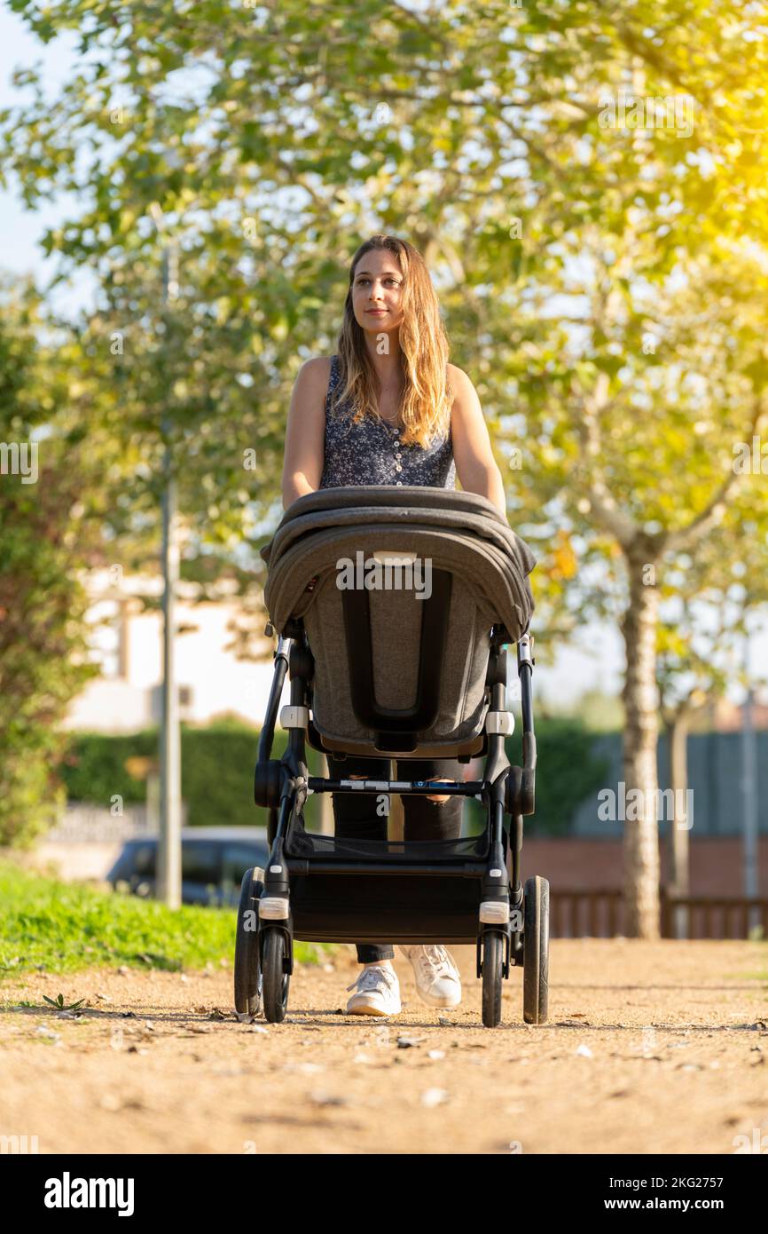 Mother and son walking with the baby stroller in the park Stock Photo
