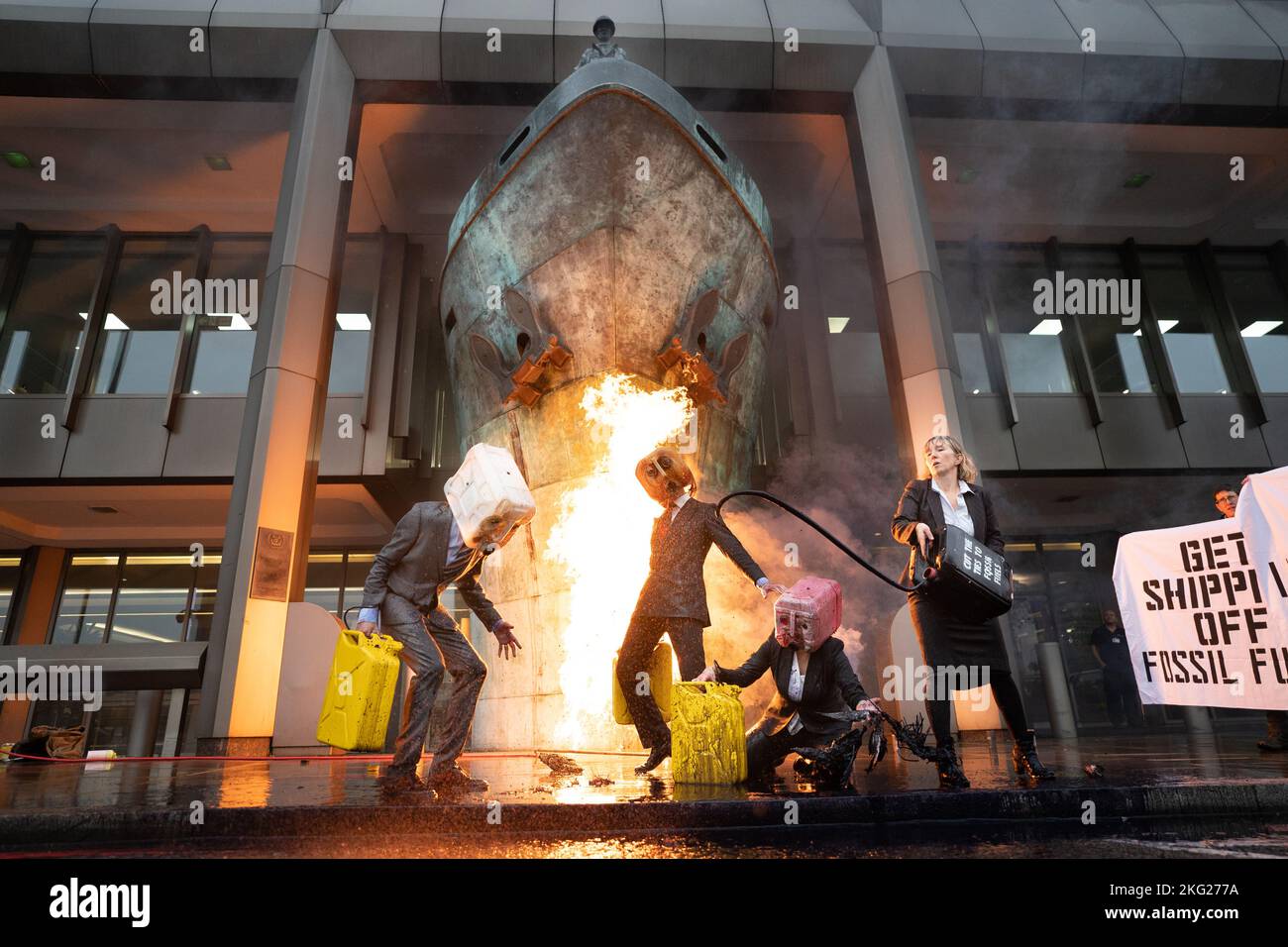 Ocean Rebellion activists demonstrate by vomiting fake oil and causing a fire during a protest outside the International Maritime Organisation (IMO), central London, which coincides with a wider series of actions focussed on cutting ties with the fossil fuel industry. Picture date: Monday November 21, 2022. Stock Photo