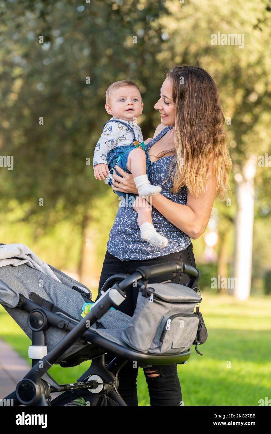 Mother and her son in the park with the baby stroller Stock Photo